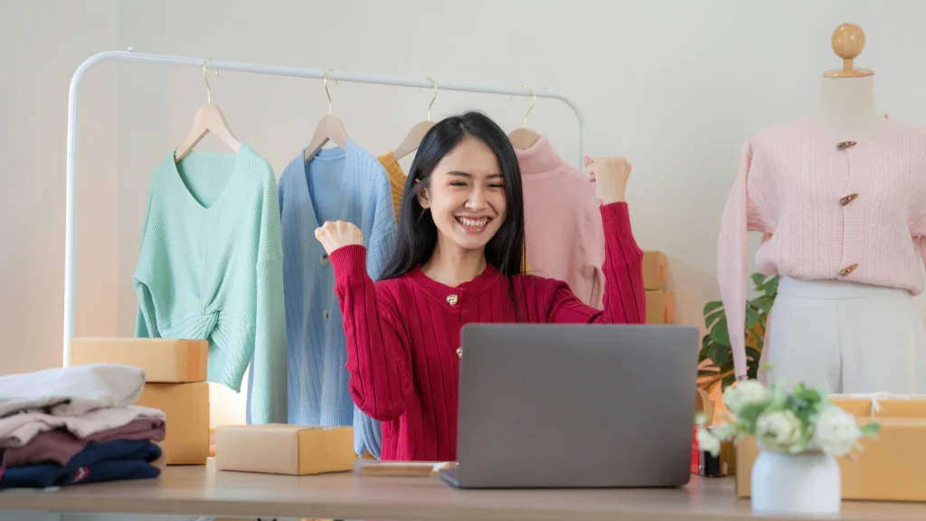 Emprendedora celebrando una venta en línea frente a su laptop
