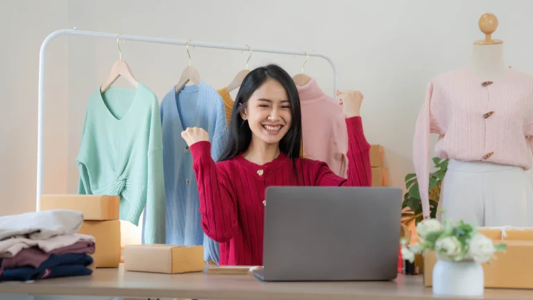 Emprendedora celebrando una venta en línea frente a su laptop
